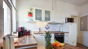 Una cocina moderna con armarios blancos, encimera de madera, microondas, tostadora y un tazón de fruta.