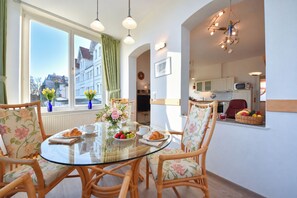 A dining area with a glass table, wicker chairs, and a view of the city through large windows. - Meerblick 05 House - with a direct view of the sea (Ahlbeck (Seebad))