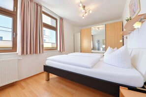 A hotel room with a bed, a window with curtains, a radiator, and a mirror. - Meerblick 05 House - with a direct view of the sea (Ahlbeck (Seebad))