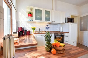 A modern kitchen with white cabinets, a microwave, a stove, and a wooden countertop. - Meerblick 05 House - with a direct view of the sea (Ahlbeck (Seebad))
