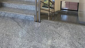 Una escalera con barandillas de metal y escalones de granito, que sube a un piso superior.