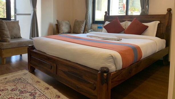 Una cama bien hecha con una colcha a rayas, un cabecero de madera y una mesita de noche con una lámpara.