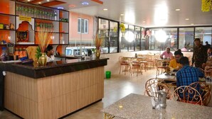 Un restaurante con mostrador de madera, sillas de metal y vistas amplias a través de grandes ventanales.