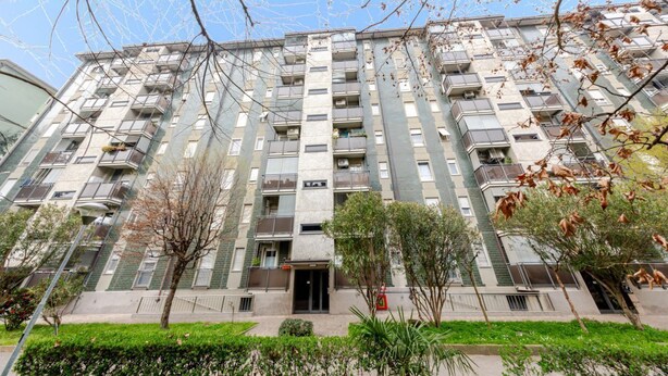 A multi-story residential building with balconies, a central entrance, and surrounding greenery. - GuestHost - Bonola M1 Underground Bright & Functional Apt x4 (Milano)