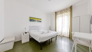 A bedroom with a bed, bedside table, chair, and a painting on the wall. - GuestHost - Bonola M1 Underground Bright & Functional Apt x4 (Milano)