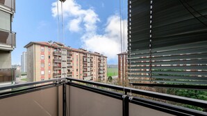 A balcony with a view of a multi-story residential building, a clear sky, and a green landscape. - GuestHost - Bonola M1 Underground Bright & Functional Apt x4 (Milano)