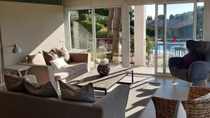 Un salon moderne avec un canapé gris, une table basse et un fauteuil en osier.