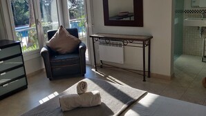 Une chambre d’hôtel avec un lit, une chaise avec un coussin, une table et une vue sur l’extérieur.