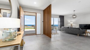 Een moderne woonkamer met een grijze bank, een televisie en een eethoek met een tafel en stoelen.