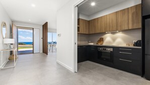 Een moderne keuken met donkere kastjes, een zwarte koelkast en uitzicht naar buiten.