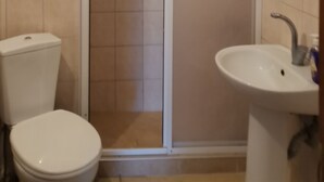 A bathroom with a toilet, sink, and a glass-enclosed shower. - Marina Pansiyon (Silivri)