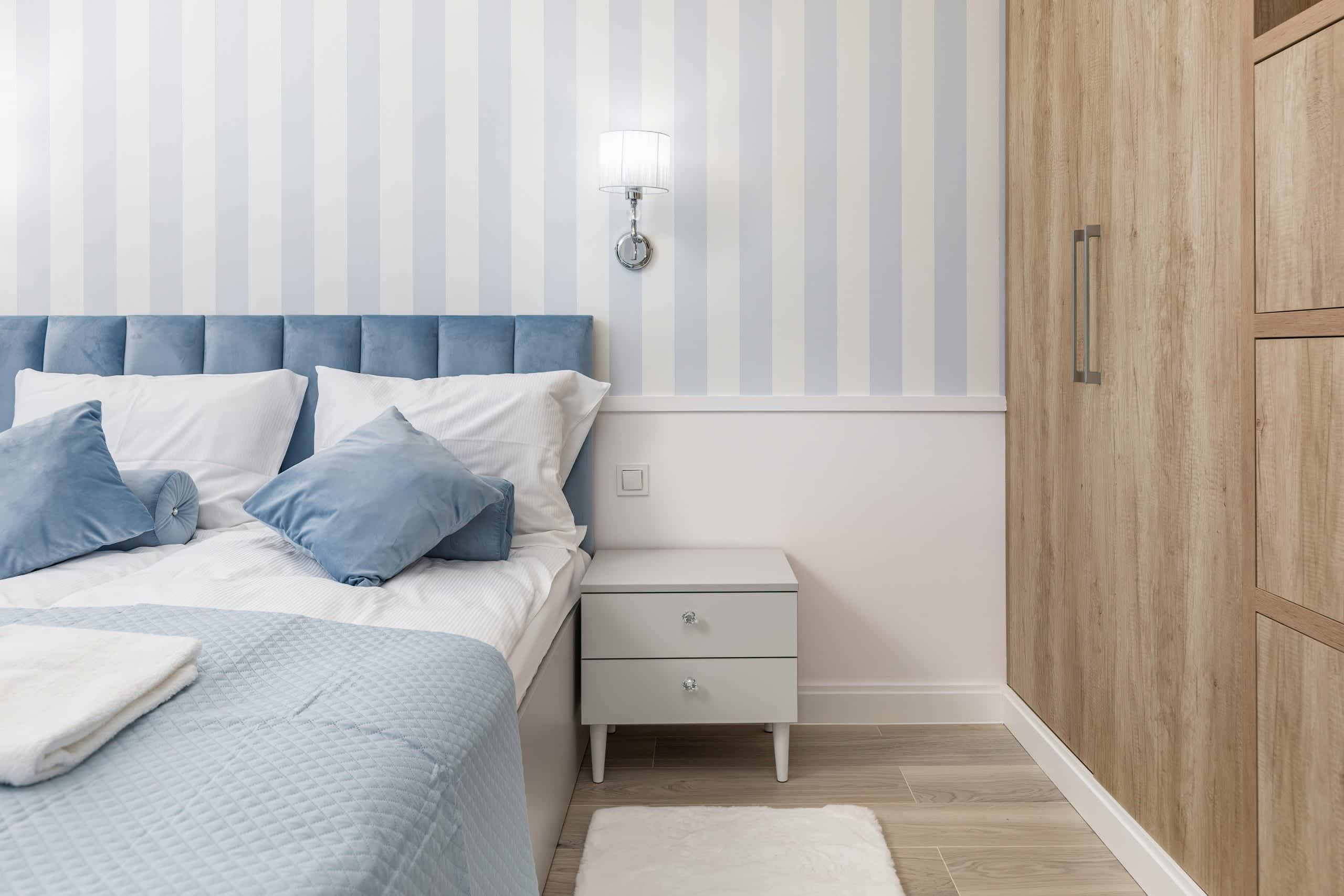 Een slaapkamer met een bed, nachtkastje en garderobe.
