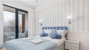 A bedroom with a bed, nightstand, and two wall-mounted lamps.