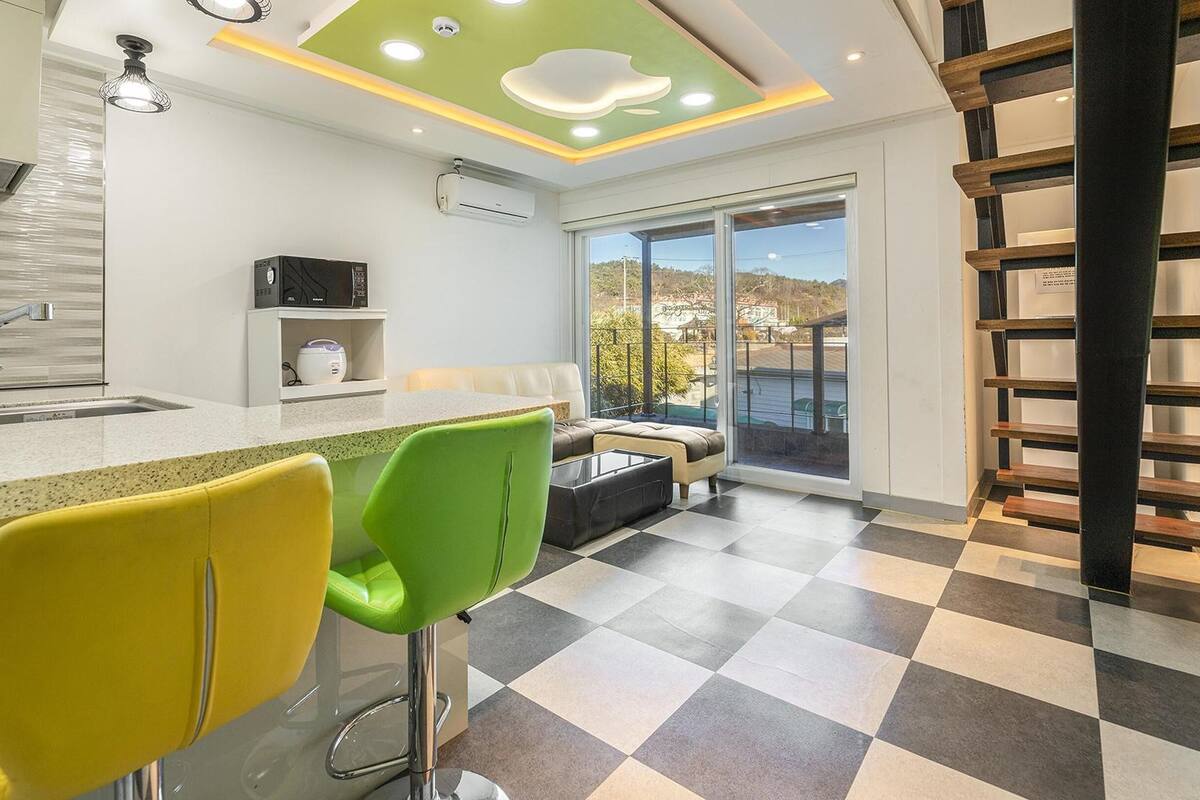 Cocina moderna con barra, comedor con sillas y vista a través de un gran ventanal corredero.