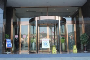 A revolving door entrance with glass panels and a sign in front. - Ruijiang International Hotel (Sandu)