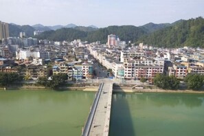 A river with a bridge, surrounded by buildings and mountains. - Ruijiang International Hotel (Sandu)
