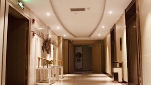 A hotel corridor with a marble floor, a reception desk, and a door at the end. - Ruijiang International Hotel (Sandu)