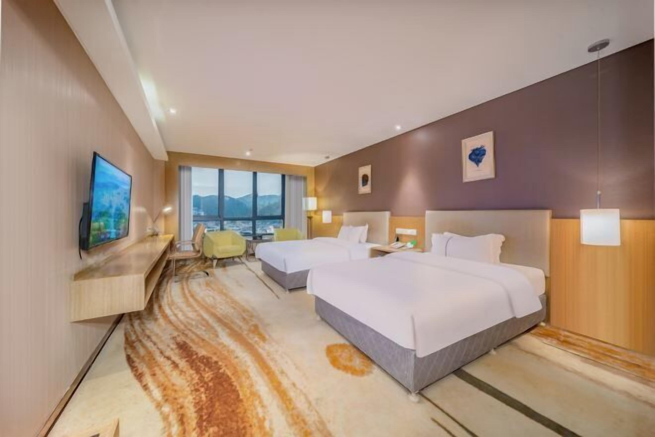 A hotel room with two beds, a TV, a large window with a view, and a carpet with a wavy pattern.
