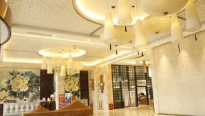 A hotel lobby with a reception desk, a seating area, and a large floral mural on the wall. - Ruijiang International Hotel (Sandu)