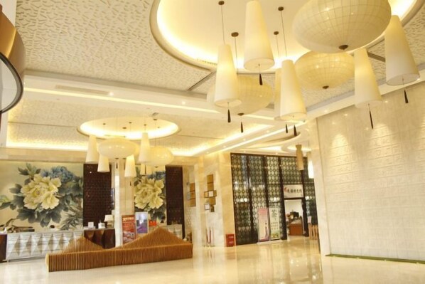 A hotel lobby with a reception desk, a seating area, and a large floral mural on the wall. - Ruijiang International Hotel (Sandu)