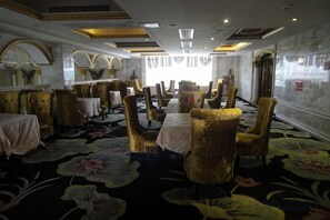 A hotel dining area with round tables, gold chairs, and a floral carpet. - Yifeng Hotel (Yifeng)