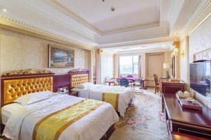 Habitación de hotel con dos camas, un escritorio, una silla, un televisor y un ventanal grande.