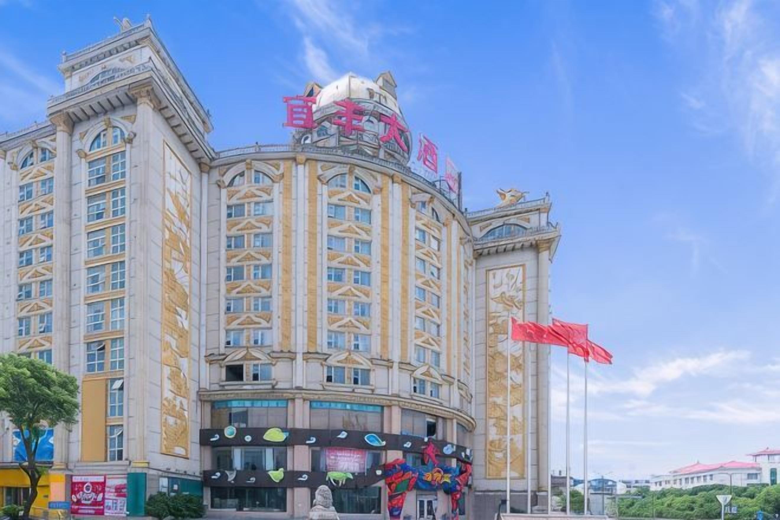 A large hotel with multiple floors, a prominent entrance, and a statue in front.