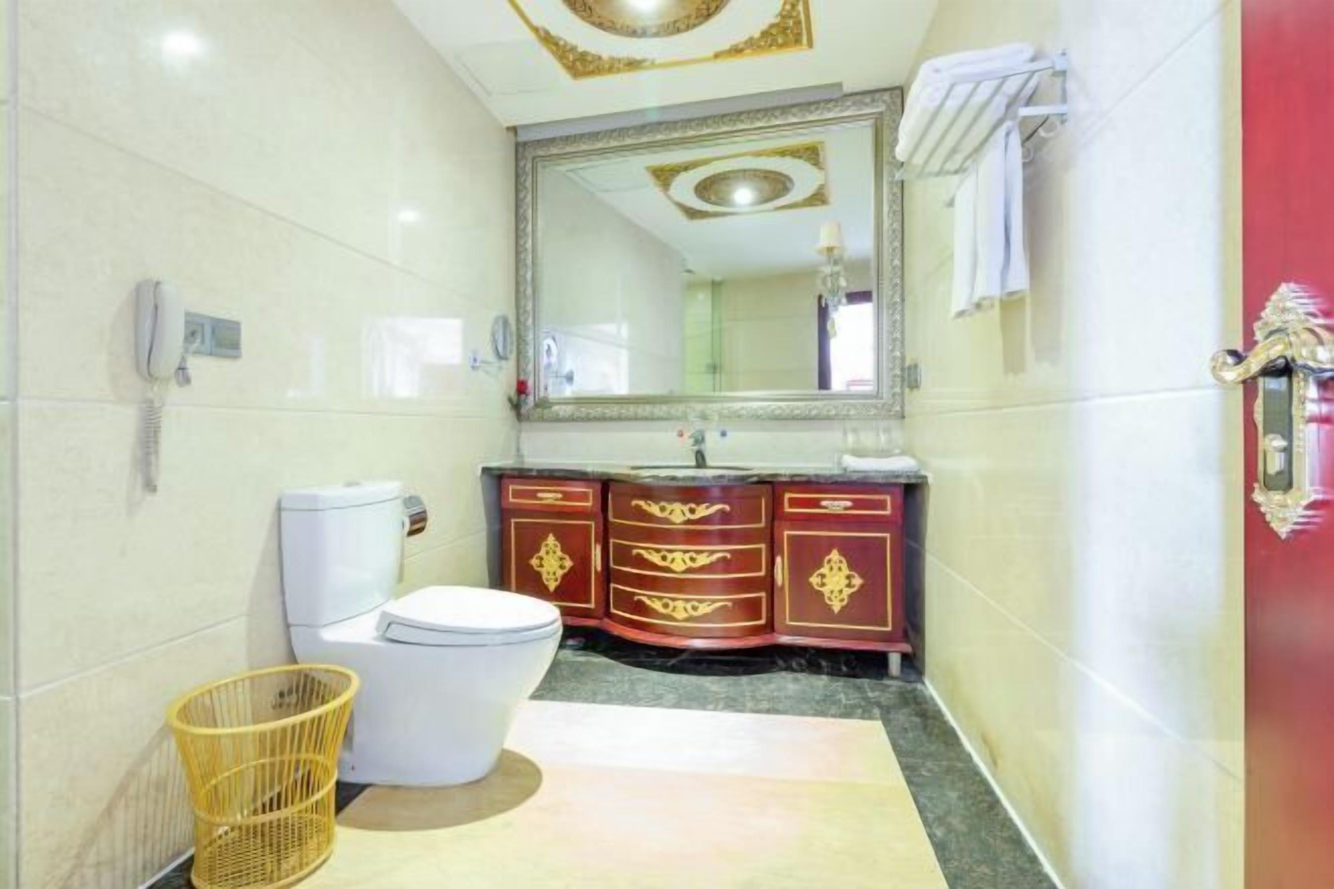 A bathroom with a toilet, a sink, a mirror, and a decorative cabinet.