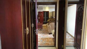 A hallway leading to a bedroom with a bed, a dresser, and a mirror.