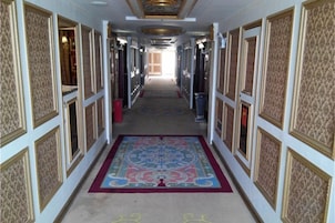 Un largo pasillo con paredes con diseño y una alfombra central.