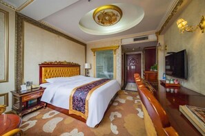 A hotel room with a large bed, a television, a desk, and a seating area. - Yifeng Hotel (Yifeng)