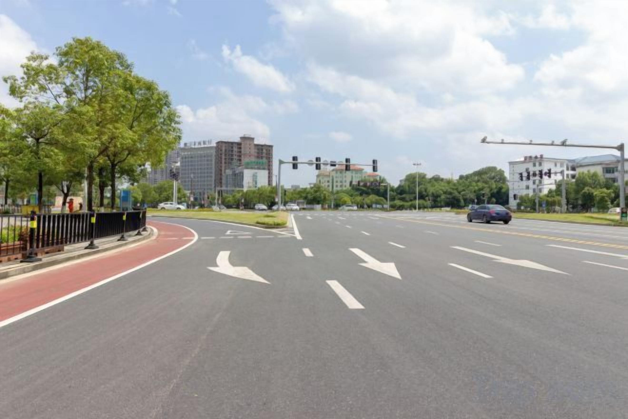 A multi-lane road with traffic lights and a pedestrian crossing.