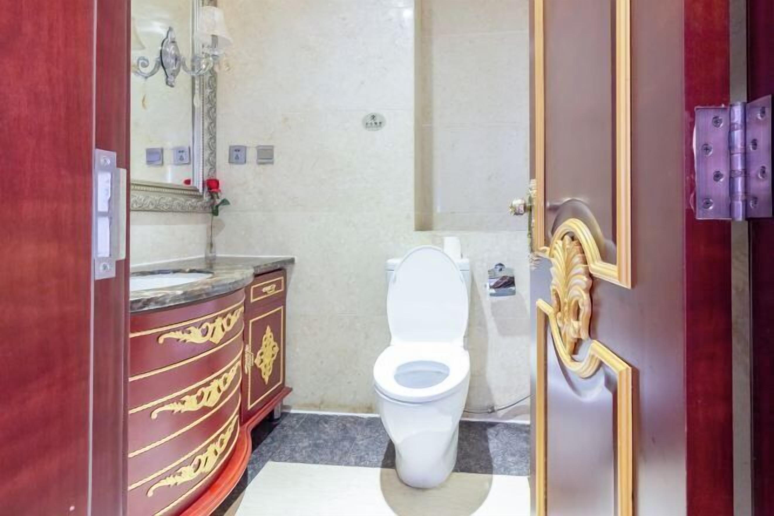 A bathroom with a marble vanity, a toilet, and a mirror.
