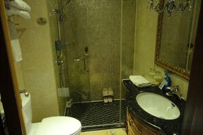 Un baño con ducha de vidrio, lavamanos e inodoro.