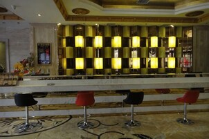 Un vestíbulo de hotel con una mesa de recepción, mostrador de registro y tres taburetes rojos.