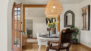 Un coin repas avec une table en bois, des chaises et un luminaire suspendu en rotin.