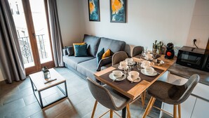 A modern living room with a dining area, grey sofa, and a coffee machine. - Description (Granada)