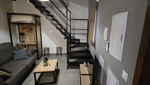 A modern living room with a sofa, coffee table, and a staircase leading to an upper level. - Description (Granada)