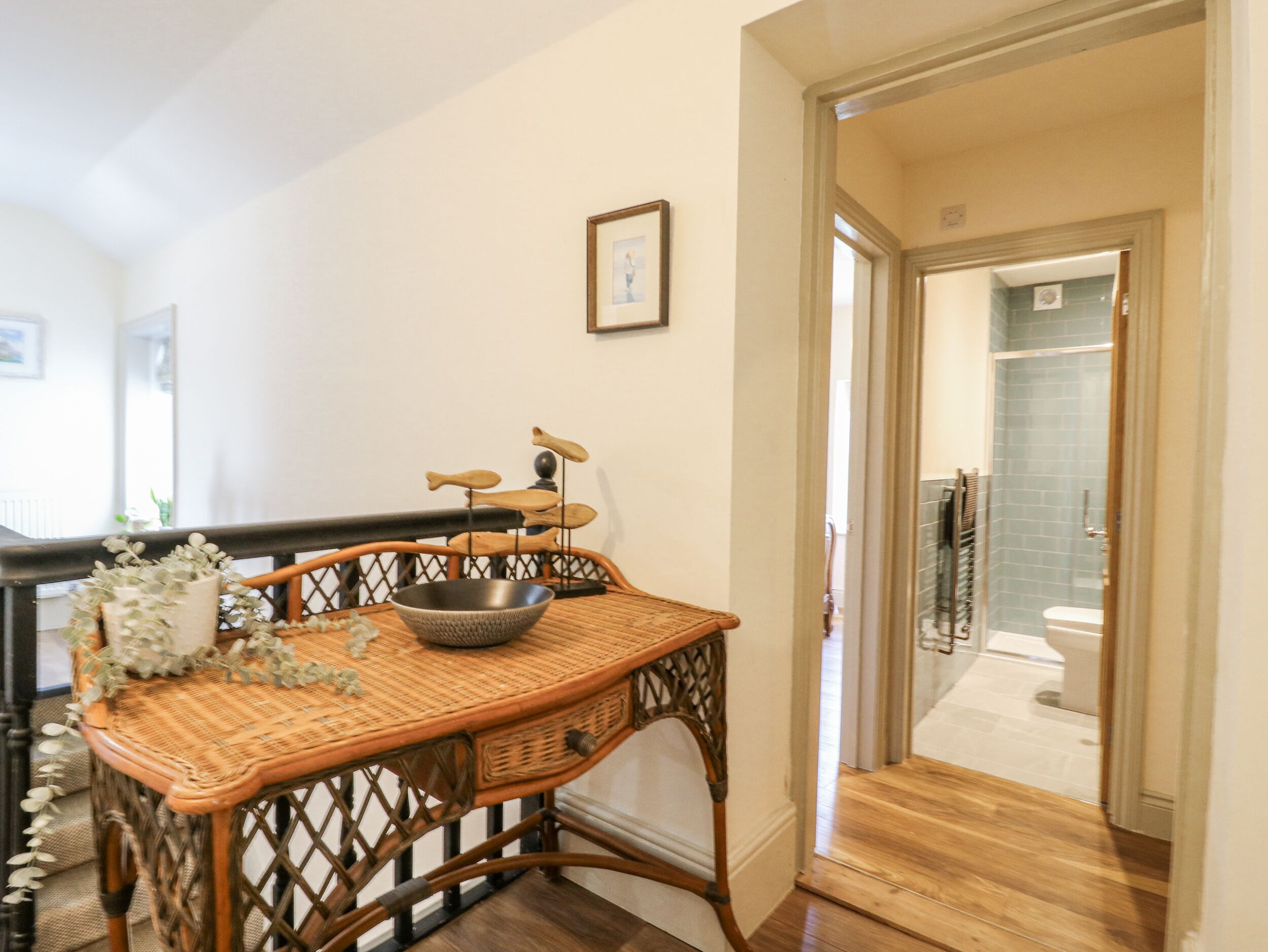 Una habitación con una mesa de mimbre, un cuenco y un cuadro en la pared.