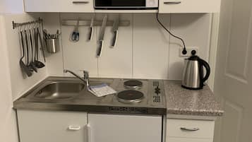 Een kleine keuken met een magnetron, koffiezetapparaat, waterkoker en een ingebouwde vaatwasser.