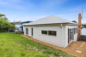 A single-story house with a sloped roof, a fenced backyard, and a view of the water. - Smith (Lorne)