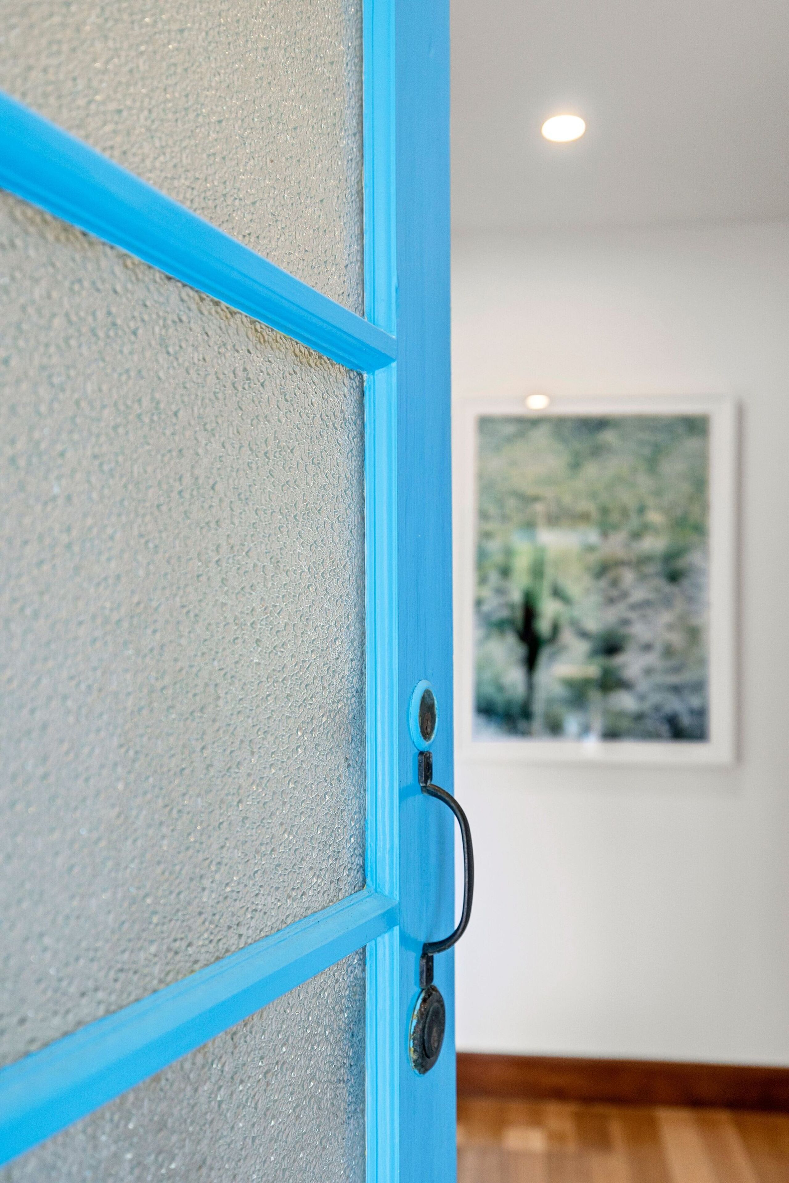 A blue-framed door with a textured glass panel, a keyhole, and a handle.