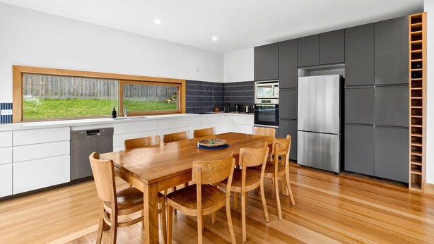 A modern kitchen with a wooden dining table and chairs, a built-in oven, and a refrigerator. - Smith (Lorne)