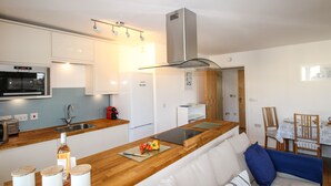 A modern kitchen with a wooden countertop, built-in oven, and a dining area with a sofa and chairs.