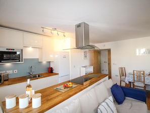 A modern kitchen with a wooden countertop, built-in appliances, and a seating area with a sofa and chairs.