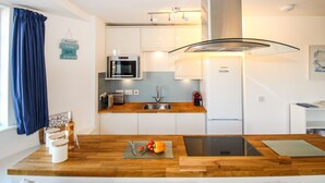 A modern kitchen with white cabinets, stainless steel appliances, a wooden countertop, and a built-in dishwasher.