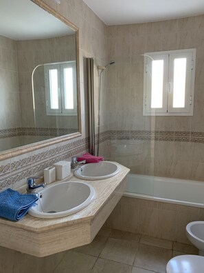 Ein Badezimmer mit zwei Waschbecken, einer Badewanne und einer Dusche.