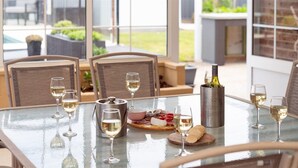 A dining table set with wine glasses, a bottle of wine, and a charcuterie board. - Happy Dayz – Comfortable accommodation with pool (Culburra Beach)