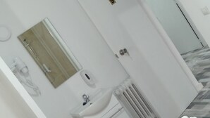 Habitación de hotel con cama, lavamanos, espejo y puerta que da a otra habitación.