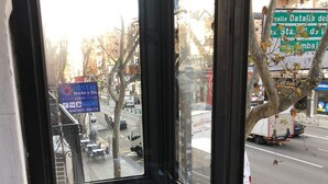Vista desde una ventana a una calle con un letrero de Hostal Noche y Dia, que indica habitaciones disponibles.